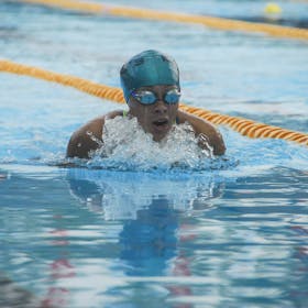 A focused swimmer competes in an outdoor swimming pool event, demonstrating skill and determination.