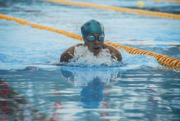 A focused swimmer competes in an outdoor swimming pool event, demonstrating skill and determination.