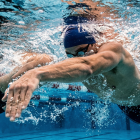 A hyper-realistic underwater shot focusing on a swimmer's hand and forearm in the "High-Elbow Catch" position. The water is churning with power, and the muscles in the arm are clearly defined. 8k, cinematic sports lighting