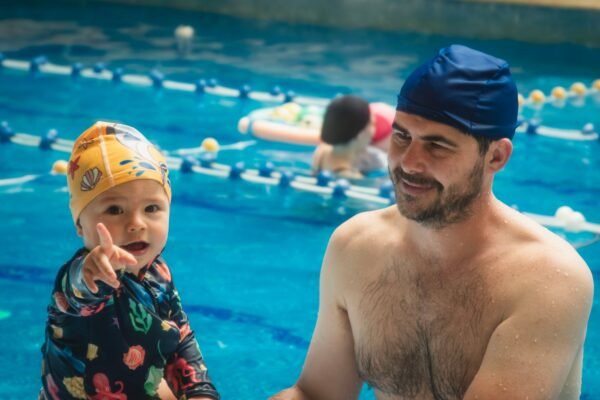 Parent helping a child learn to swim in a pool