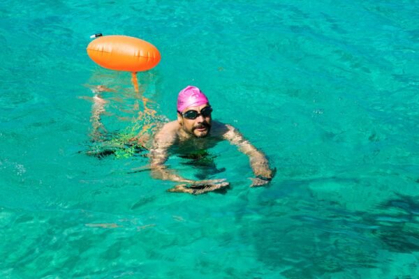 Open water swimmer wearing goggles and safety swim buoy