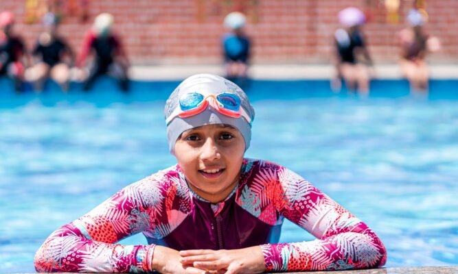 Child wearing swimming goggles during a pool lesson