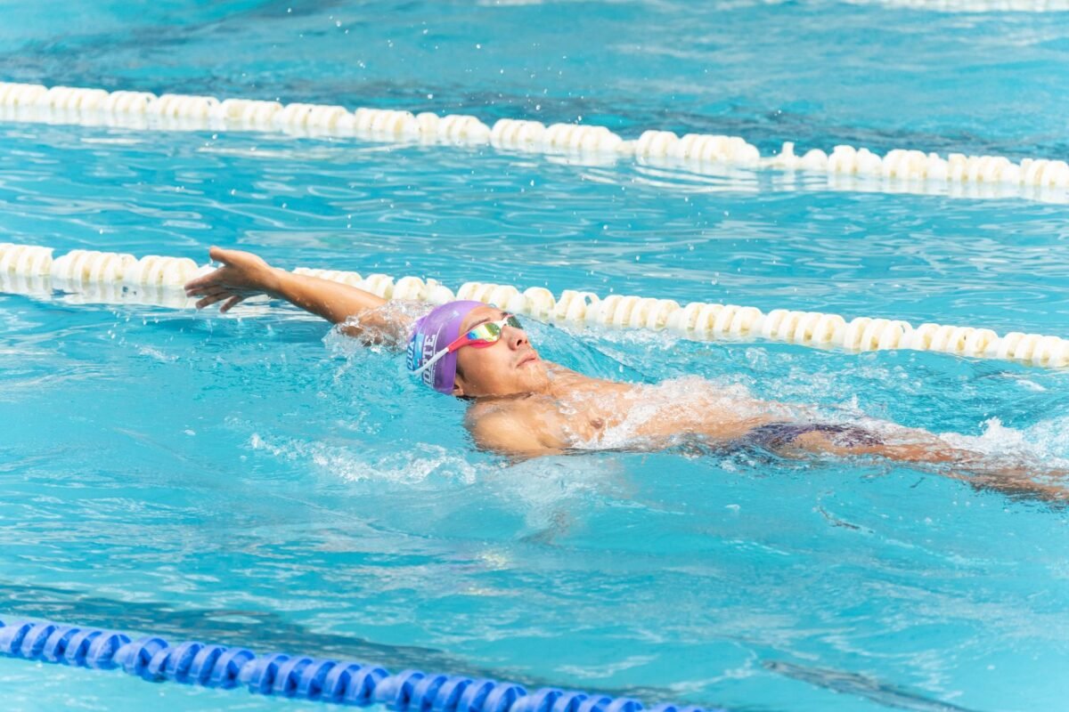 Swimmer wearing mirrored goggles in bright pool light