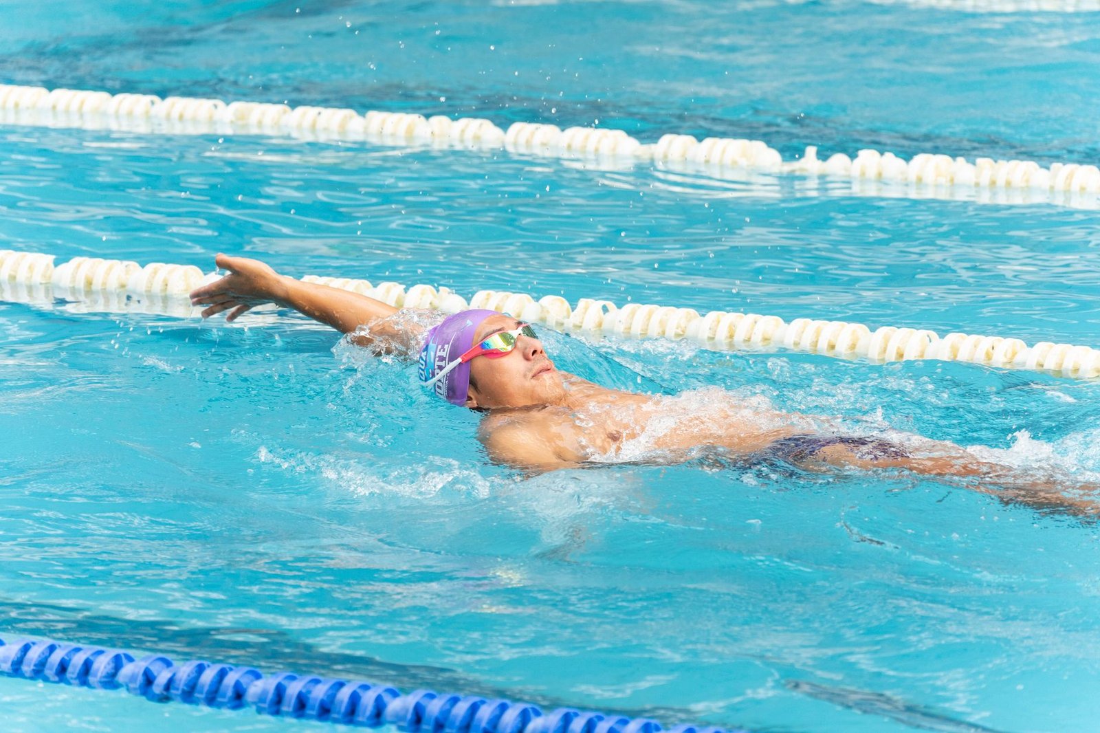 Swimmer wearing mirrored goggles in bright pool light